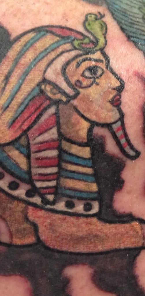 Ägyptische Pharaonin mit geschmücktem Kopf und bunten Streifen auf ihrem Gewand.